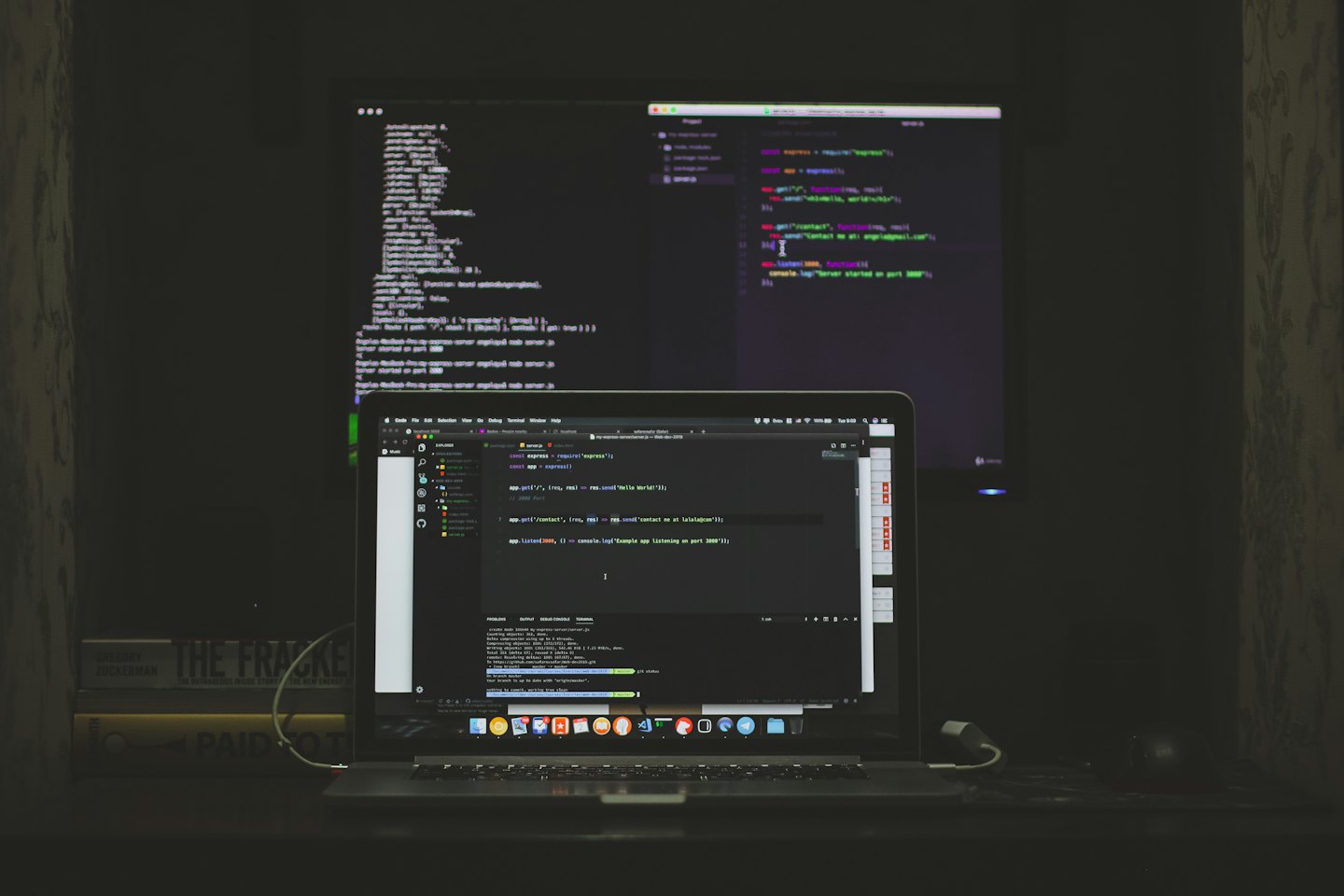 Laptop und externer Monitor mit Code auf einem Schreibtisch.